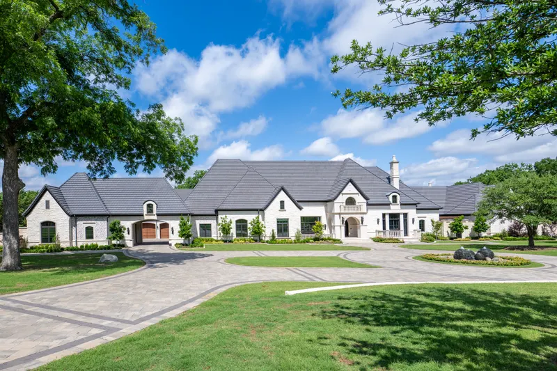 Front elevation with slate roof and paver motor court under blue sky at Bella Terra Estate, Parker TX