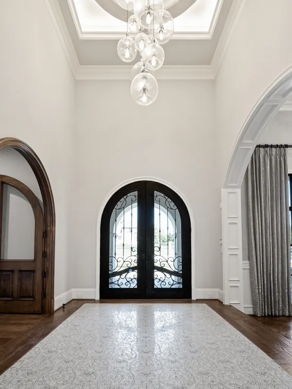 Entry foyer with arched wrought iron doors and a cascading glass globe chandelier