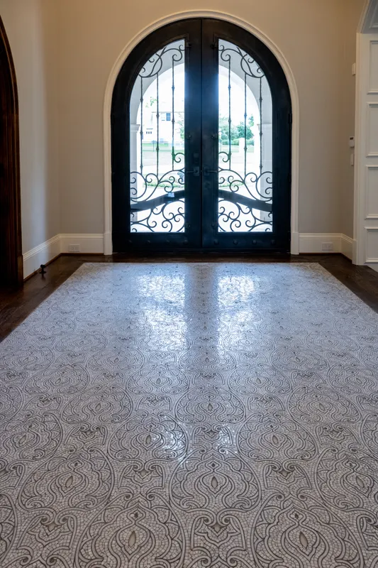 Foyer mosaic tile medallion floor leading to arched wrought iron entry doors