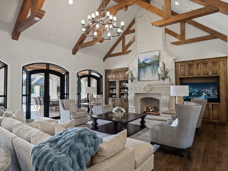 Vaulted family room with exposed wood trusses and a carved cast stone fireplace