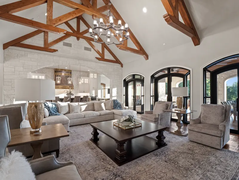 Family room under timber trusses with a limestone wall opening to the kitchen