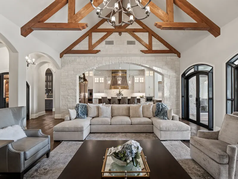 Family room sectional framed by a stone arch opening to the chef's kitchen