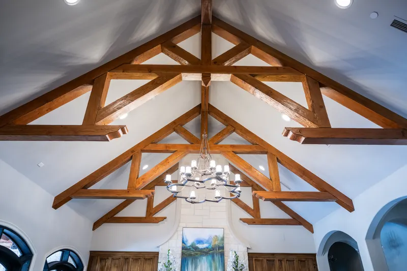 Cathedral ceiling detail with stained timber trusses and an iron chandelier