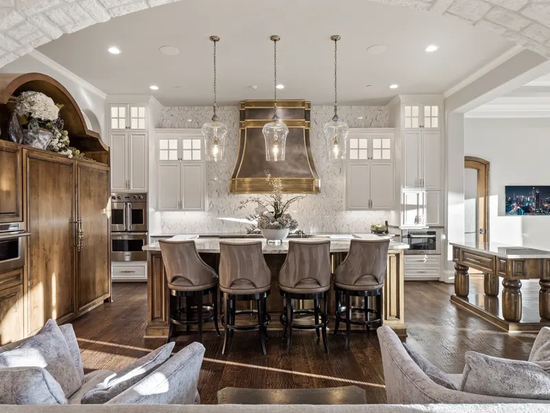 Chef's kitchen with antique brass range hood and a marble island seating four