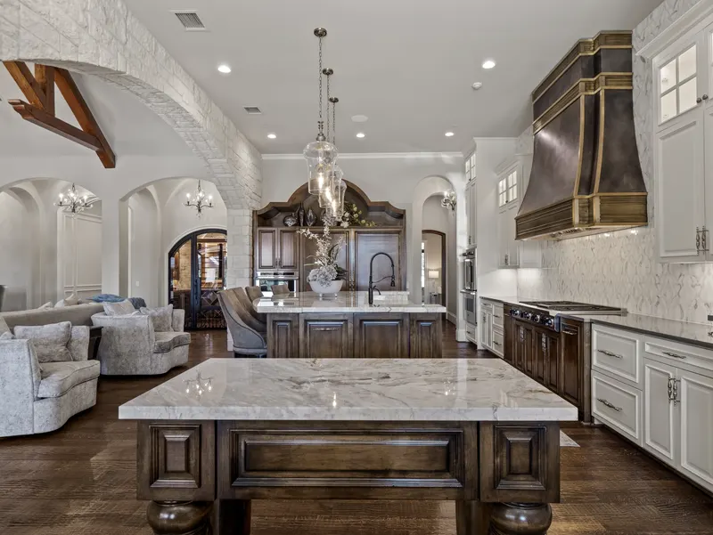 Chef's kitchen with dual marble islands, brass range hood and Viking range