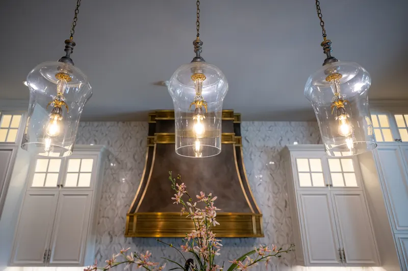 Hand-blown glass pendants above the kitchen's antique brass range hood