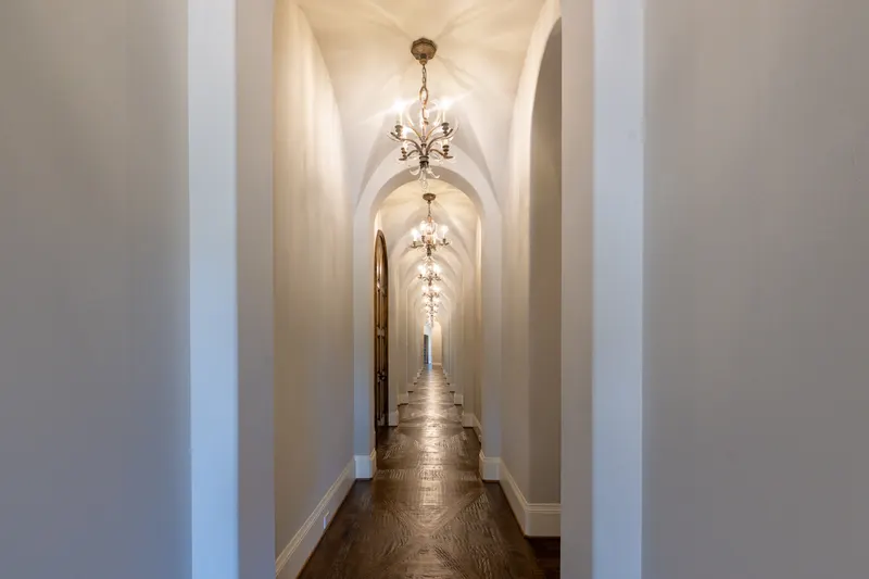 Groin-vaulted hallway lined with chandeliers and herringbone wood flooring