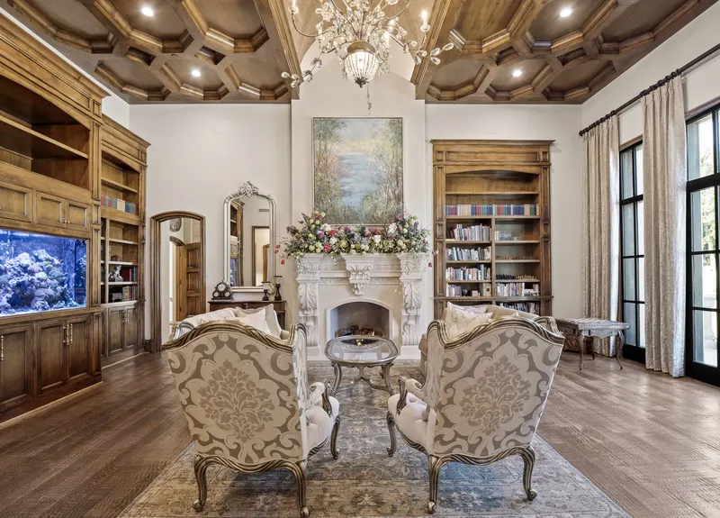 Library with coffered wood ceiling, carved fireplace and coral reef aquarium