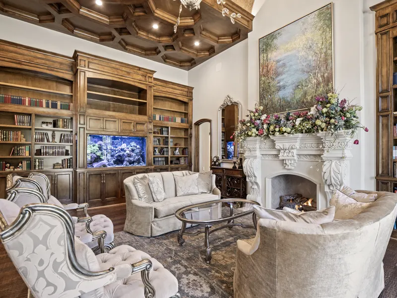 Library built-ins with a 440-gallon coral reef tank and floral-draped mantel
