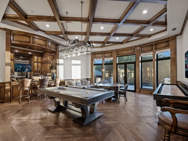 Game room pool table and card table beside the paneled wet bar and windows