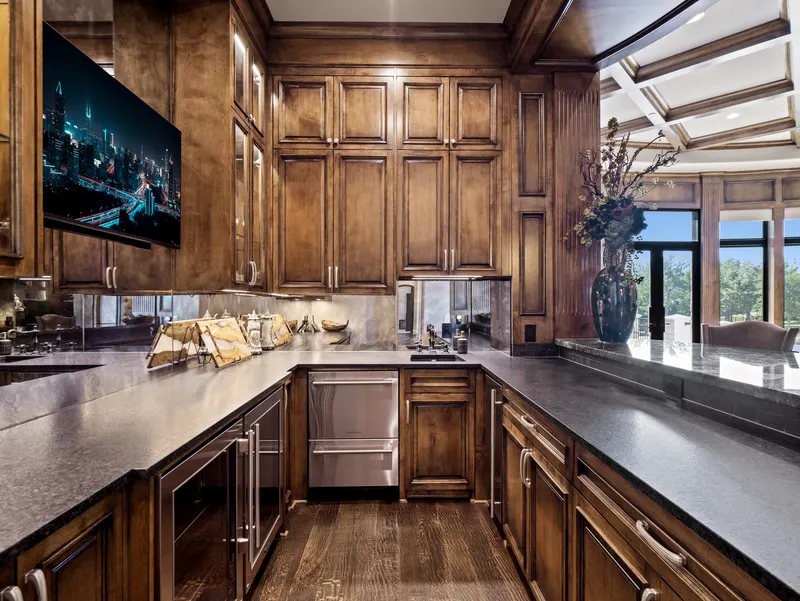 Entertaining bar with dark stone counters, mirrored backsplash and wine fridge