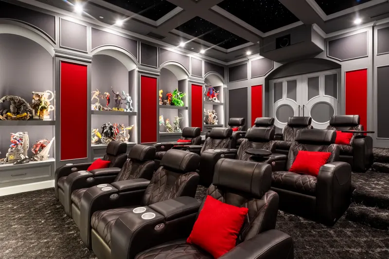 Theater recliners with red accent pillows beneath the starlit tray ceiling