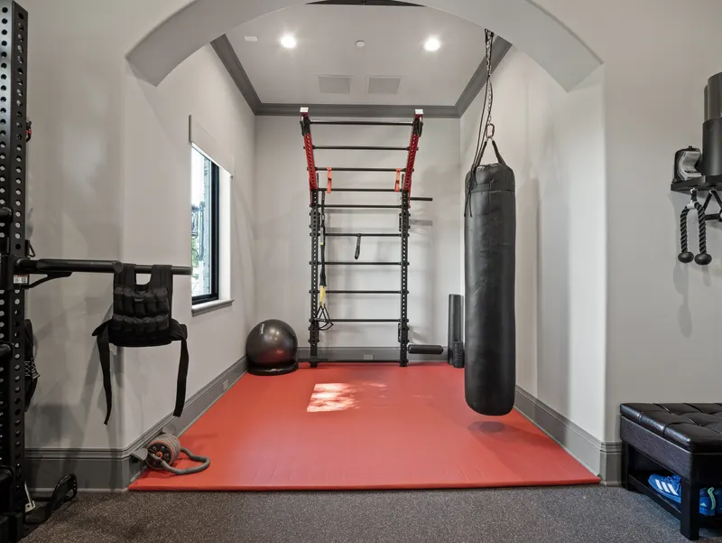 Gym training alcove with heavy bag, wall bars and a red matted floor