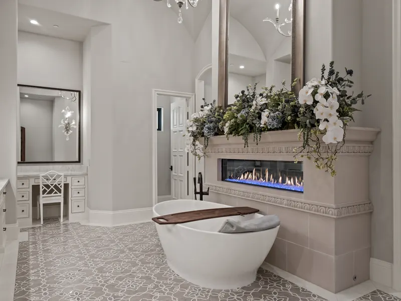 Master bath soaking tub beside a linear fireplace and makeup vanity nook