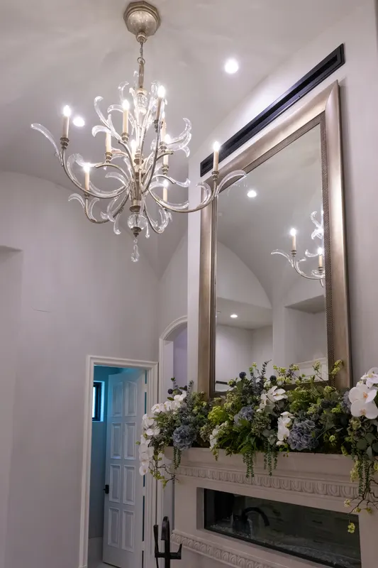 Master bath chandelier and silver-framed mirror beneath a barrel-vaulted plaster ceiling