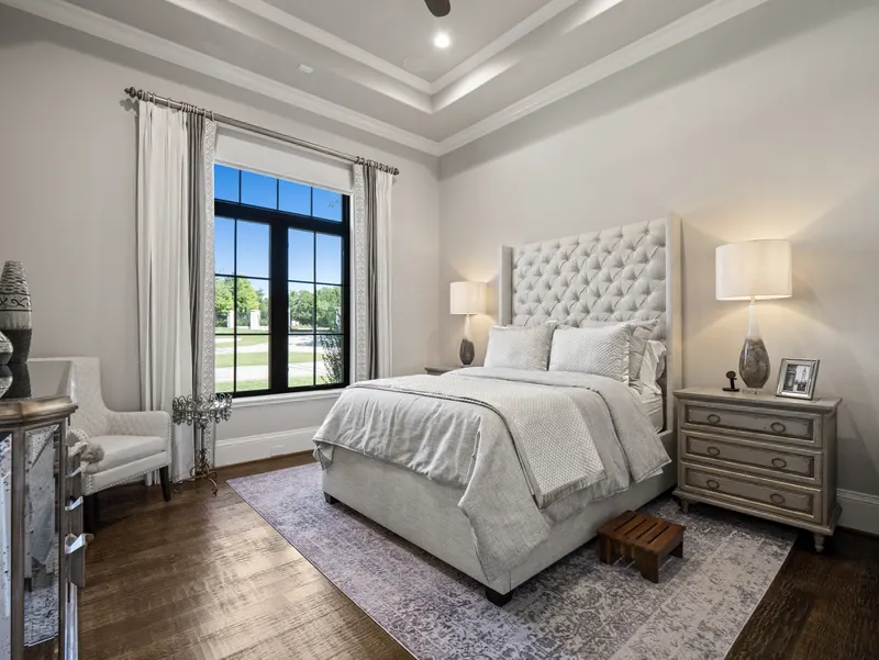 Guest suite bedroom with tufted wingback headboard, tray ceiling and tall black-framed window