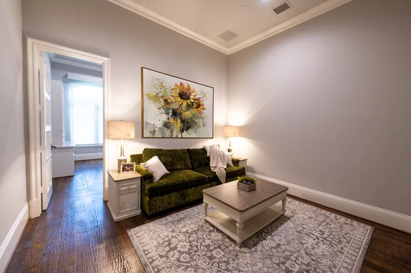 Guest suite sitting room with olive velvet sofa and sunflower painting above