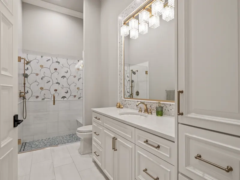 Guest bath with crystal vanity lights, terrazzo-framed mirror and vine-patterned shower tile