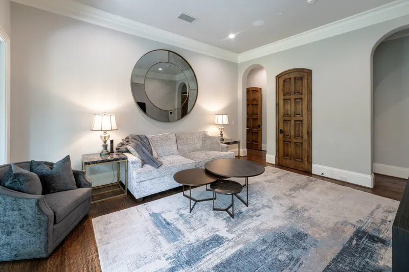 Guest apartment living room with round mirror, nesting tables and arched wood door