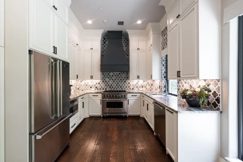 Guest apartment kitchen with black vent hood, arabesque marble backsplash and stainless range