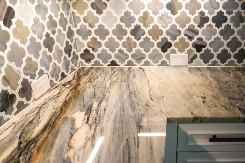 Quartzite countertop with gold veining meeting the arabesque marble backsplash