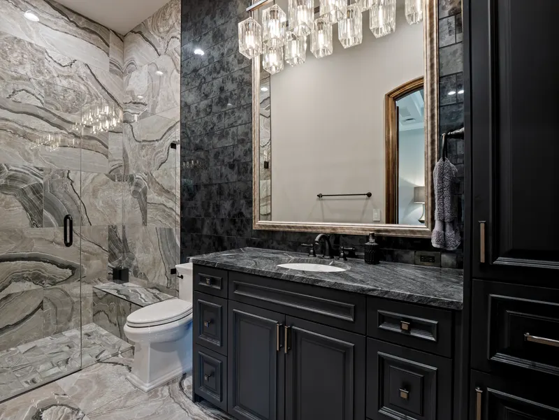 Guest apartment bath with black vanity, crystal chandelier and book-matched marble shower