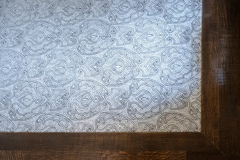 Intricate blue and white mosaic tile floor bordered by wide-plank oak flooring