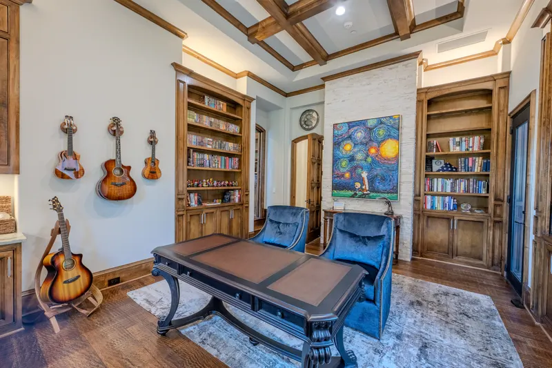 Library office with coffered wood ceiling, built-in bookcases and hanging guitar display