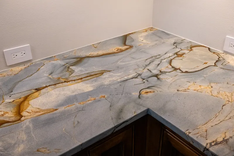Quartzite countertop corner with amber veining above dark stained cabinetry