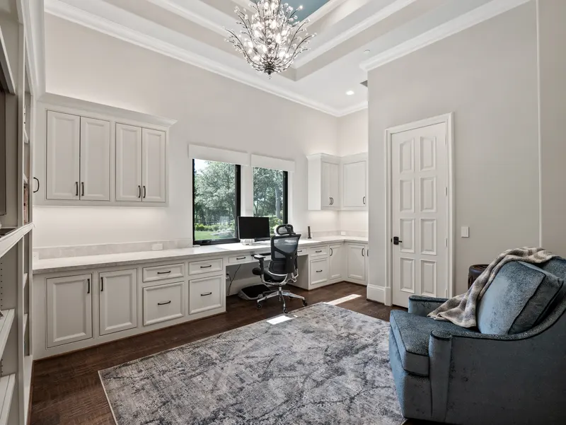 Second office with white built-in desks, crystal branch chandelier and tray ceiling