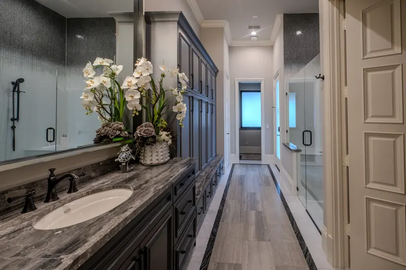 Gallery-style bath with dark marble vanity, orchid display and glass walk-in shower
