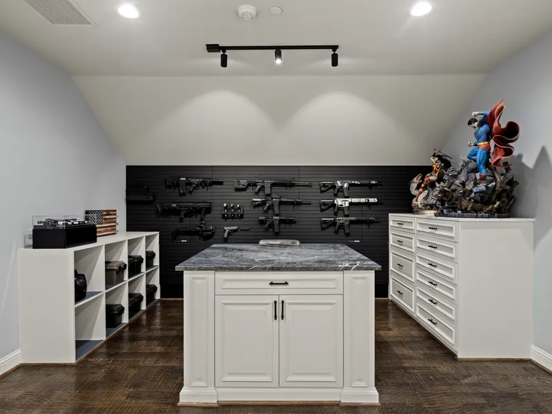 Armory and safe room with wall-mounted firearm racks and a marble-topped work island