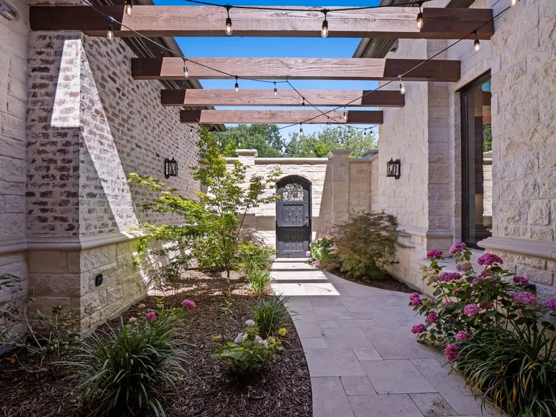 Stone side courtyard with cedar pergola, string lights and arched gate at Bella Terra Estate, Parker TX