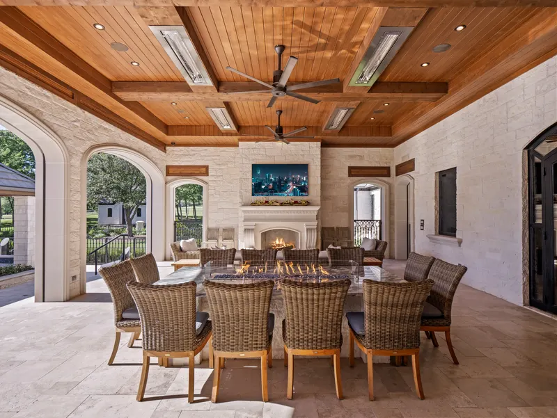 Outdoor dining under cedar beams with fire table and cast stone fireplace at Bella Terra Estate, Parker TX