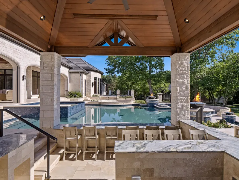 Swim-up bar with marble counter and barstools under a cedar-ceiling pool cabana at Bella Terra Estate, Parker TX