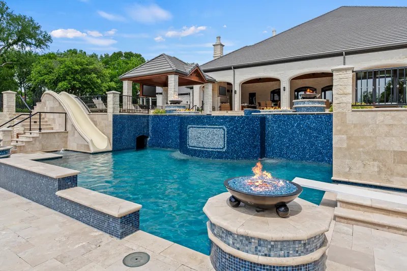 Resort pool with white waterslide, grotto tunnel and copper fire bowl at Bella Terra Estate, Parker TX