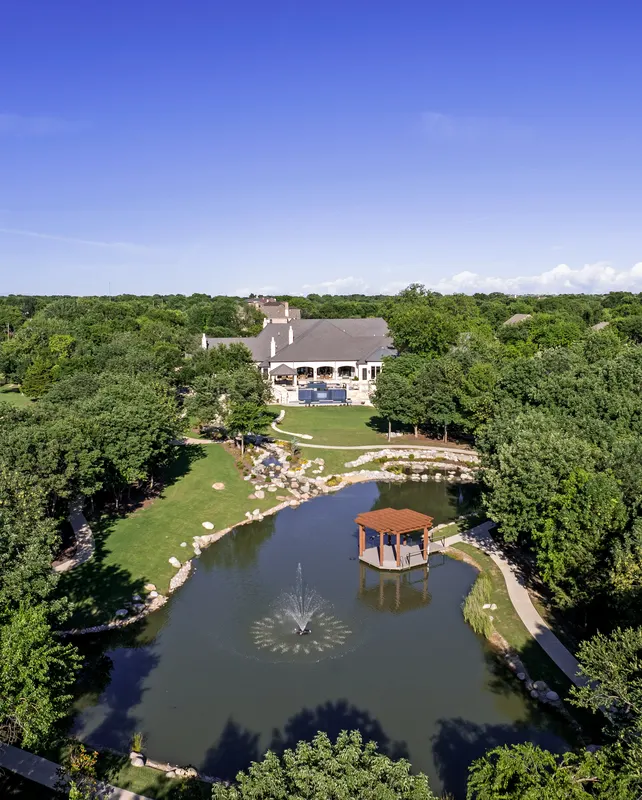 Aerial of the half-acre pond with aerating fountain and dock pergola at Bella Terra Estate, Parker TX