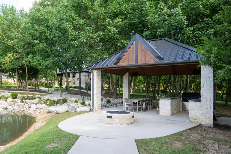 Lakeside pavilion with outdoor grill kitchen, dining table and fire pit at Bella Terra Estate, Parker TX