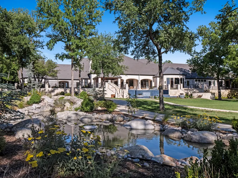 Boulder-lined stream and waterfalls below the rear terrace steps at Bella Terra Estate, Parker TX