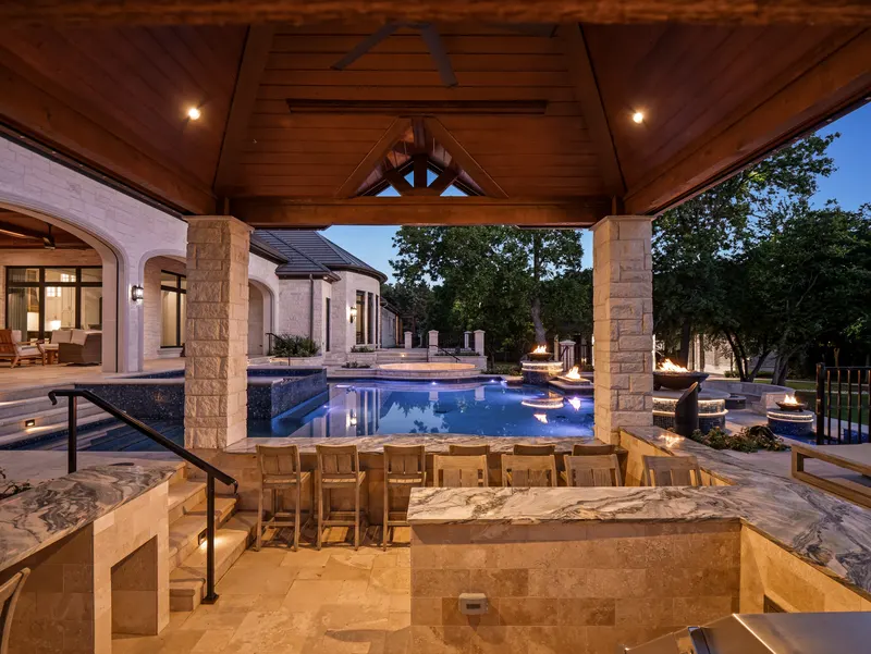 Swim-up bar and barstools under the lit cabana with the pool glowing blue at nightfall