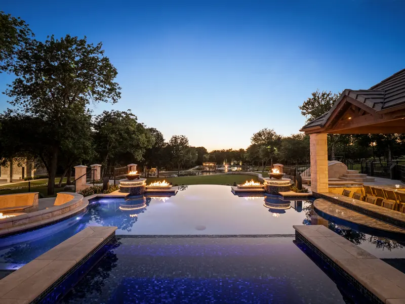 Twilight view down the pool axis past twin fire bowls to the lawn at Bella Terra Estate, Parker TX