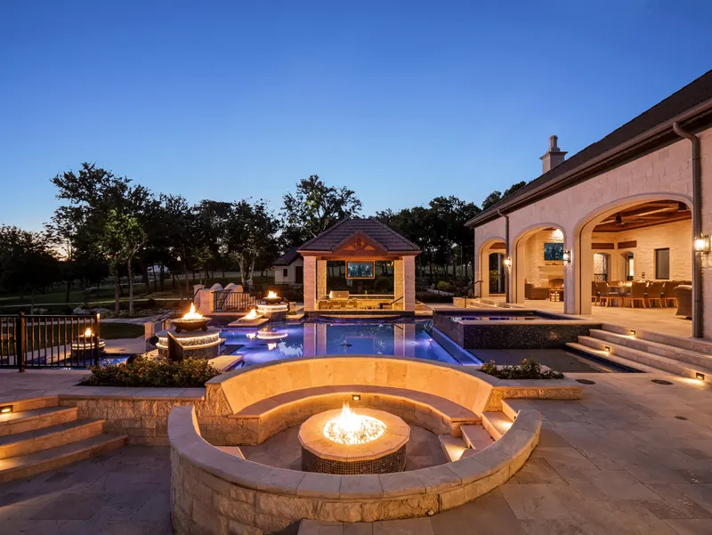 Sunken fire pit lounge lit at dusk beside the pool and cabana at Bella Terra Estate, Parker TX