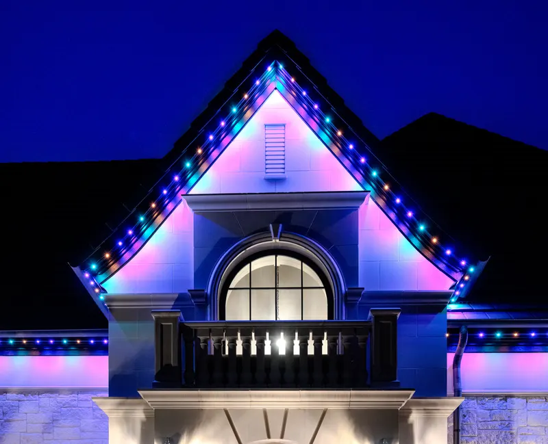 Gabled entry dormer with arched window and balcony outlined in color-changing lights at Bella Terra Estate, Parker TX