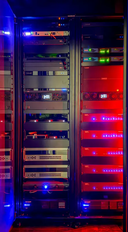 Structured wiring rack stacked with amplifiers and network gear glowing red and blue