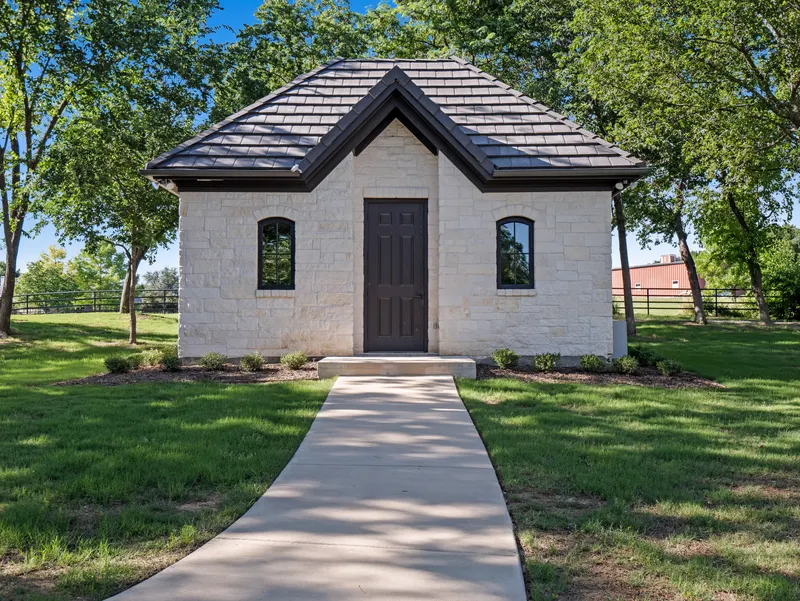 Stone cottage with arched windows and a paved path across the lawn at Bella Terra Estate, Parker TX